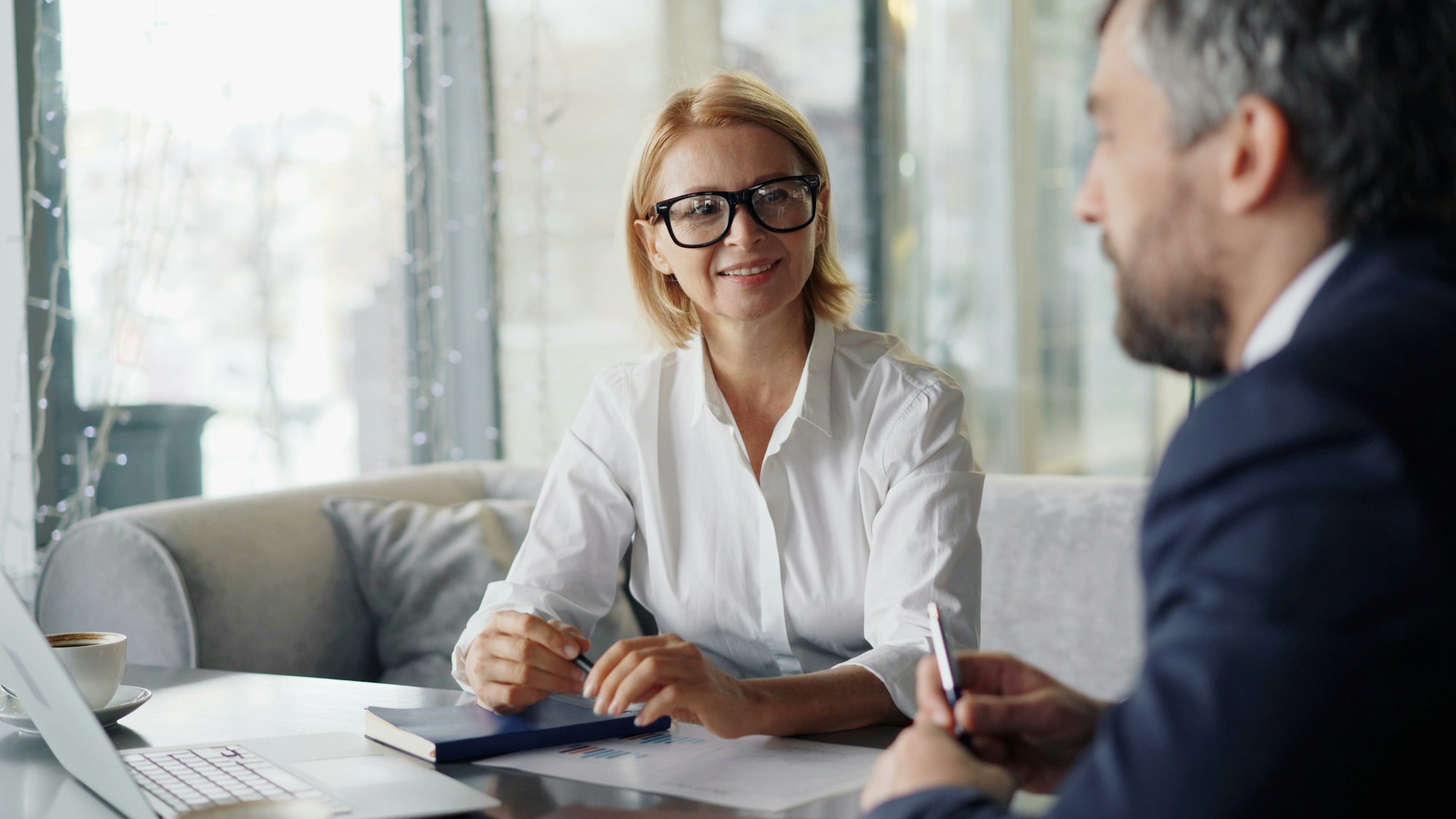 Une conseillère souriante échange avec un client autour d'un dossier